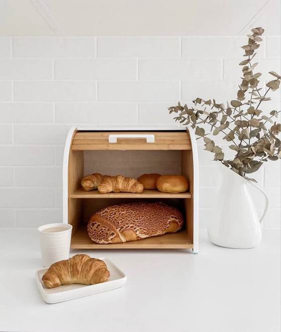 The bread box open with bread beside a jug of eucalyptus