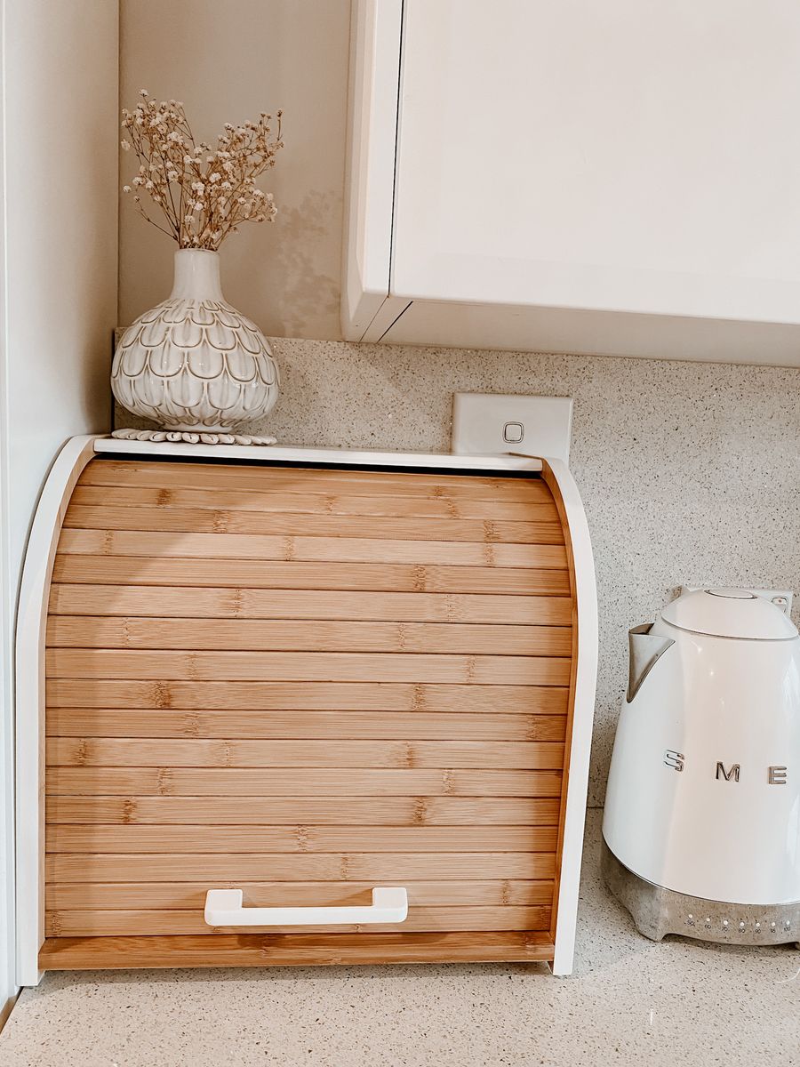 Bread box closed on a speckled stone bench, beside a white kettle